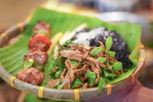 Eine Person, die einen Teller mit Essen auf einem Bananenblatt hält in der Unterkunft Lavender Homestay Măng Đen in Kon Von Kla