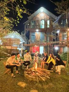 eine Gruppe von Menschen, die vor einem Haus um ein Feuer sitzen in der Unterkunft Lavender Homestay Măng Đen in Kon Von Kla