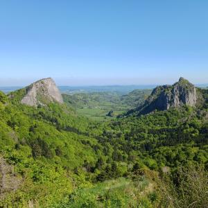 Una vista de un valle con árboles y montañas. en La Source - appart 85 m2 & terrasse privée rdc, en Orcival