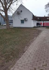 ein weißes Gebäude mit einem Baum neben einem Bürgersteig in der Unterkunft Átrium Dunaujváros in Dunaújváros