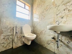 un baño con inodoro y lavabo en Green Heaven Mysore Homestay, en Mysore