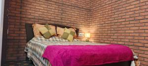 een slaapkamer met bakstenen muren en een bed met een roze deken bij Loto Villa in Bangalore +17 foto's