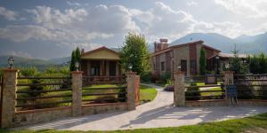 a fence in front of a house with mountains in the background at Pozar Park Rooms in Orma
