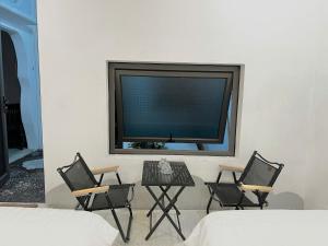 a tv on a wall with three chairs and a table at The Mountain Homestay & Cafe in Văn Lâm