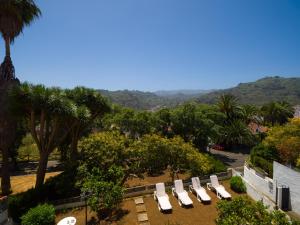 eine Reihe weißer Liegestühle in einem Park mit Palmen in der Unterkunft Pension Casa Esperanza in Teror