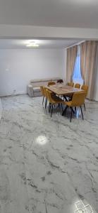 a dining room with a table and chairs on a marble floor at Casa Maxi in Gherla
