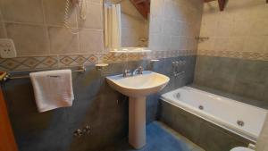 a bathroom with a sink and a bath tub at Taiquen Apart Hotel in San Martín de los Andes