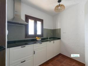 a kitchen with white cabinets and a window and a sink at Living Artenara - CAVE HOUSE & SILENCE Adults Only in Artenara +71 photos