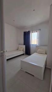 a white room with two beds and a window at Résidence Guebbas in Skikda