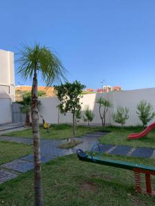 a playground with a palm tree and a slide at Résidence Guebbas in Skikda