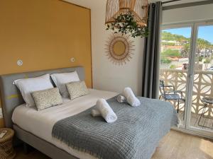 a bedroom with a bed with pillows and a balcony at HOTEL RESTAURANT LA COTE REVEE in Leucate