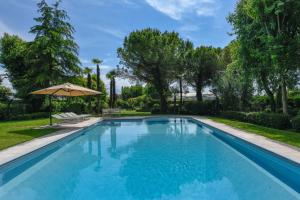 a swimming pool in a yard with an umbrella at Villa Maria by Garda FeWo in Moniga