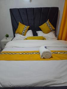 a large bed with yellow and white pillows at Shalom Stays in Machakos