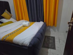 a bedroom with a bed with yellow curtains at Shalom Stays in Machakos