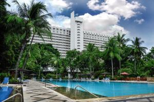 a large hotel with a swimming pool and palm trees at Hotel Borobudur Jakarta in Jakarta