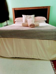 a large bed with pink and white sheets and pillows at Zagorski’s Bed and breakfast in Bloubergstrand