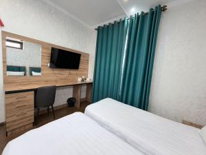 a bedroom with two beds and a desk with a television at Soro Hotel in Dushanbe +47 photos