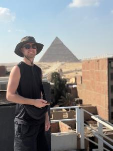 a man wearing a hat standing in front of the pyramids at Prince Pyramids Hotell in Cairo