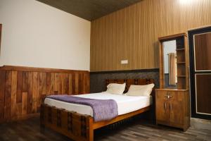 a bedroom with a wooden bed and a mirror at The Rain Tree resort in Kutta