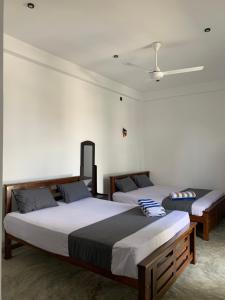 a bedroom with two beds and a ceiling at The Rosemary House in Weligama