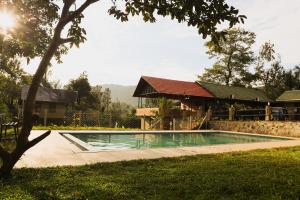 a swimming pool in front of a house at The Rain Tree resort in Kutta