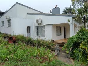 een wit huis met een veranda en een tuin bij 179 Guesthouse on Mountain Drive in Mbabane +4 foto's