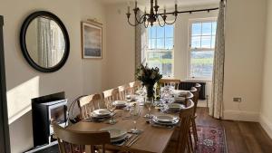 a dining room with a table with chairs and a mirror at 1 Bossiney House - Bude Cornwall in Bude