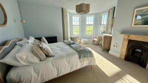 a bedroom with a white bed with a fireplace at 1 Bossiney House - Bude Cornwall in Bude