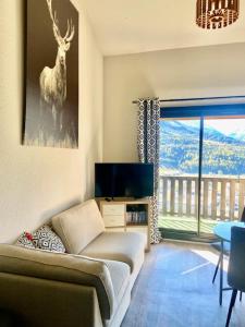 a living room with a couch and a picture of a deer at Appartement Hauteur Barcelonnette Vue Exceptionnelle in Barcelonnette
