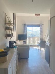 a kitchen with a counter and a table and a window at Appartement Hauteur Barcelonnette Vue Exceptionnelle in Barcelonnette
