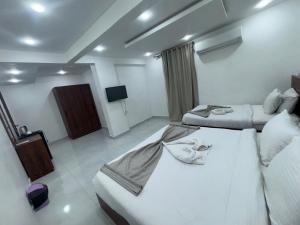 een hotelkamer met twee bedden en een flatscreen-tv bij Prince Pyramids Hotell in Caïro