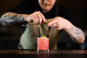 Un hombre con tatuajes preparando una bebida en una mesa. en Hótel Jökulsárlón - Glacier Lagoon Hotel, en Gerdi