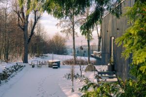 a snow covered yard with benches and a building at Rest Hill -Domek z balią i sauną - Everslow in Sosnówka