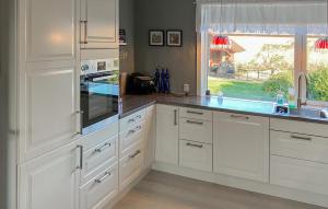 3 Bedroom Cozy Home In Bøvlingbjerg في Bøvlingbjerg: مطبخ بخزائن بيضاء ومغسلة ونافذة