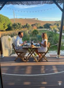 Ein Mann und eine Frau sitzen an einem Tisch auf einem Deck in der Unterkunft Maçussa Country House in Massuça