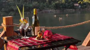 una mesa de picnic con una botella de vino y una copa en Pont Inn Nong Khiaw, en Nongkhiaw