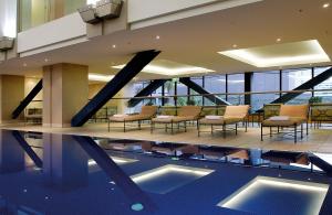 a hotel lobby with a pool and chairs and a building at Grand Millennium Auckland in Auckland