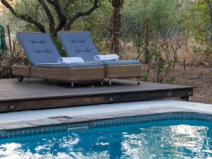 two chairs sitting on a deck next to a swimming pool at Nzenga Lodge in Hoedspruit +15 photos