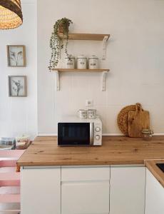 een keuken met witte kasten en een magnetron op een aanrecht bij Casa titamari in Casarabonela +25 foto's