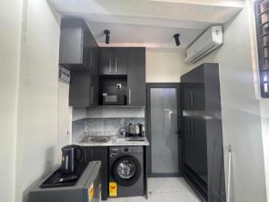 a small kitchen with black cabinets and a washing machine at La Villa Petite in Lapaz