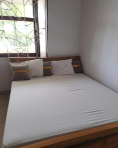 a bed with white sheets and pillows in a room at Creek apartment in Kilifi