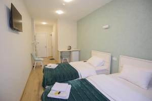 a hotel room with two beds and a desk at Hotel Caucasus in Tbilisi City