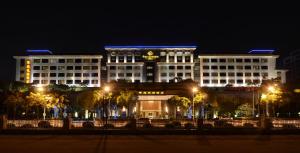un grande edificio bianco con un orologio sopra la notte di Dongguan Well Garden Hotel a Dongguan