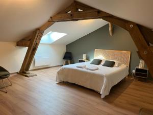 ein Schlafzimmer mit einem großen Bett im Dachgeschoss in der Unterkunft Les Gîtes du Colombier in Ollé