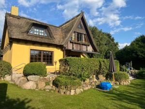ein gelbes Haus mit einem Regenschirm im Hof in der Unterkunft Landhaus Pauline in Kröpelin