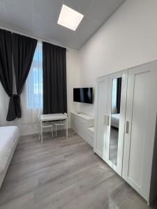 a white room with a bed and a desk and a television at Viva Residence in Calderara di Reno +12 photos