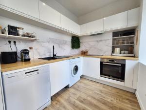 a kitchen with white cabinets and a washer and dryer at La Pause Briochine in Saint-Brieuc