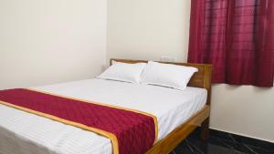 Seetha Residency في تيروفانمالي: سرير في غرفة ذات ستارة حمراء