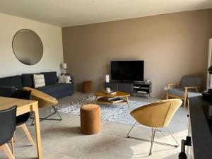 ein Wohnzimmer mit Sofa und Fernseher in der Unterkunft Les Gîtes du Colombier in Ollé