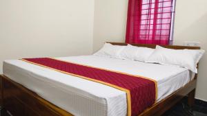Seetha Residency في تيروفانمالي: سرير في غرفة مع نافذة حمراء
